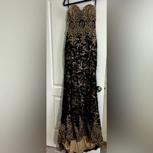 Sleeveless black dress with gems and a long tail.